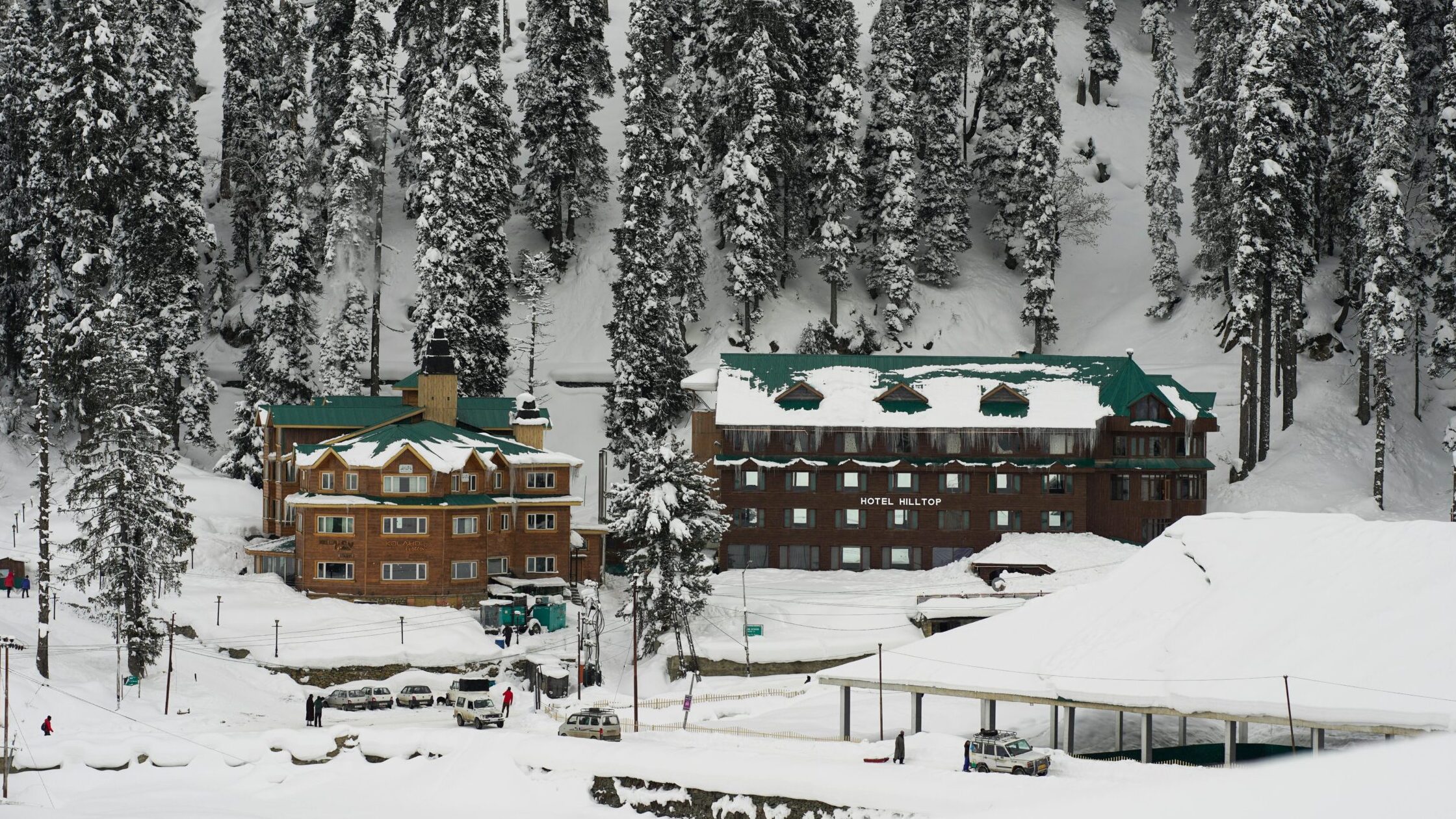 A picturesque view of snow-covered Hotel Hilltop in the serene winter landscape of Gulmarg, Kashmir.