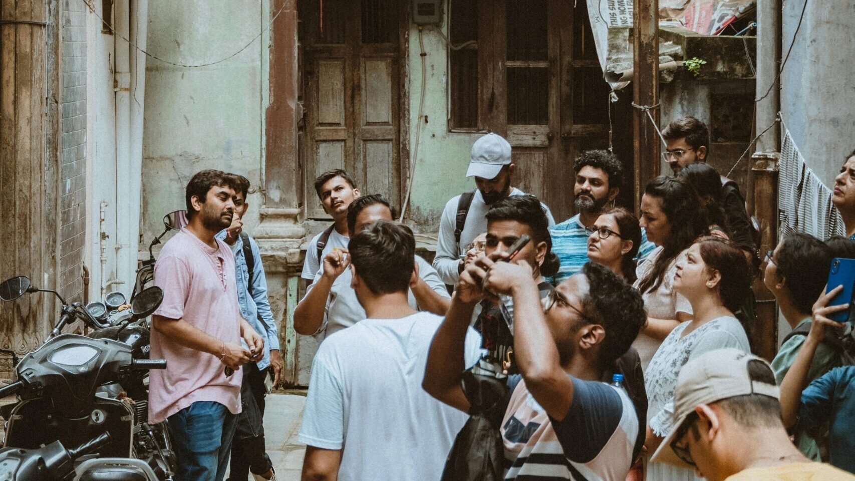 Tourists gathered in an old alleyway in Ahmedabad, India, learning about local history.